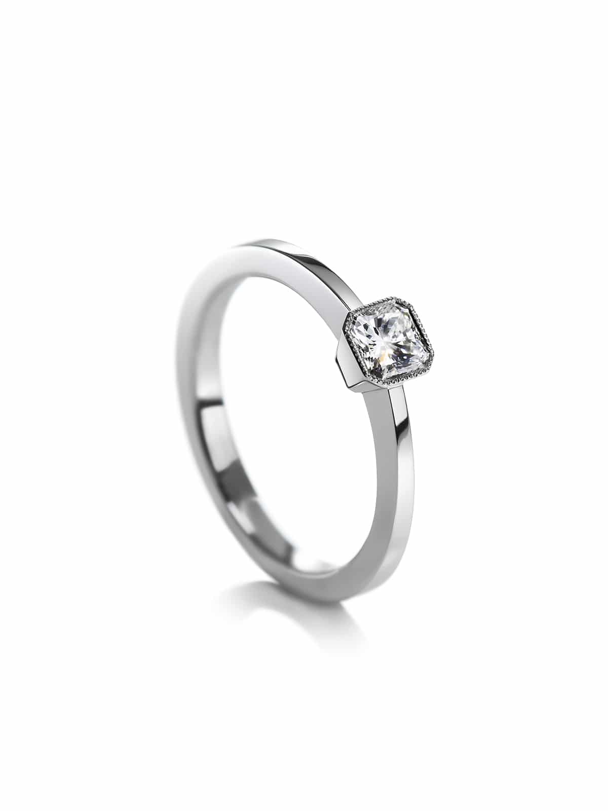 A platinum solitaire ring with a radiant cut diamond in milgrain set.