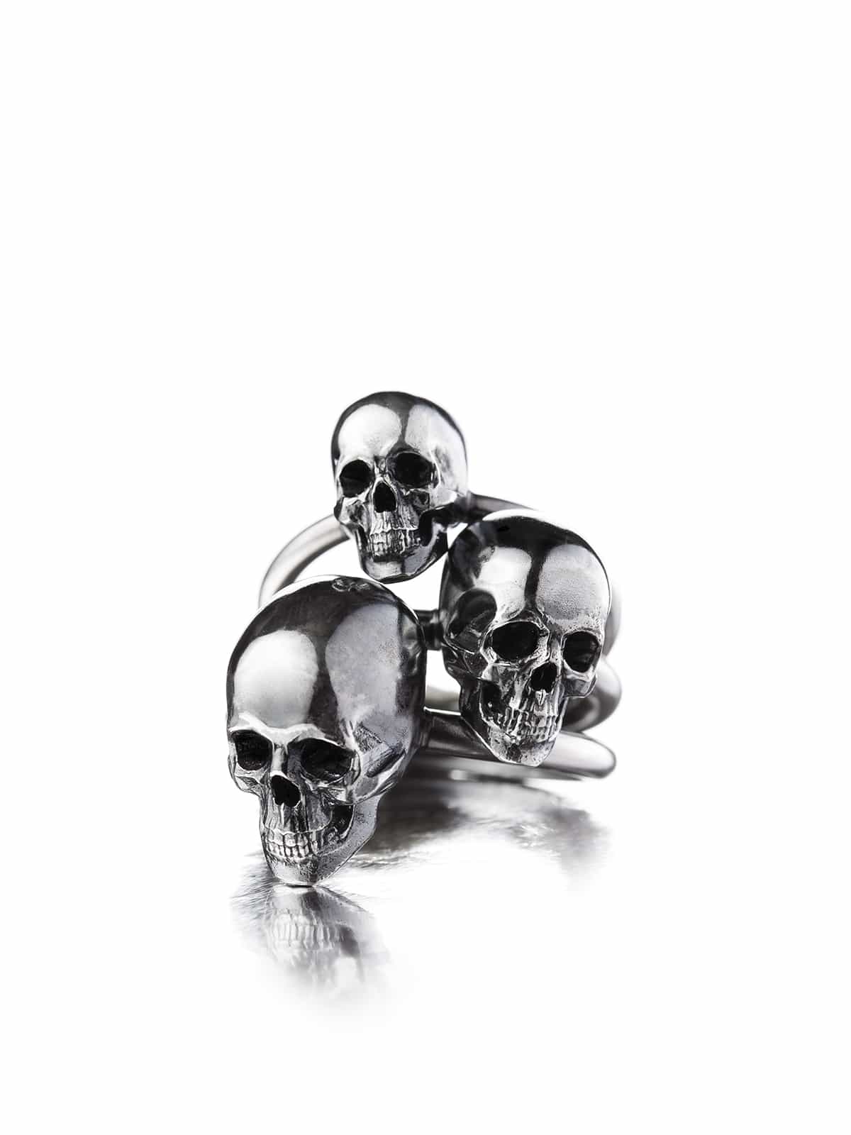 A large silver skull ring, with a design that includes multiple skulls stacked together.